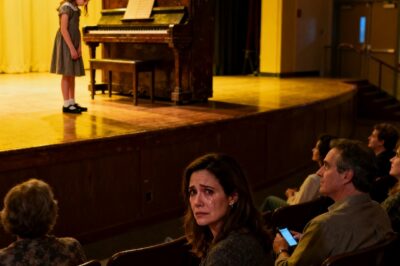 At my daughter’s school talent show, no one clapped for her. Even the judges looked bored. I heard a parent whisper, “she’s the ‘poor girl’ from that single mom.” I held back tears-until a stranger stood up from the back row. The room went silent as he took the stage.